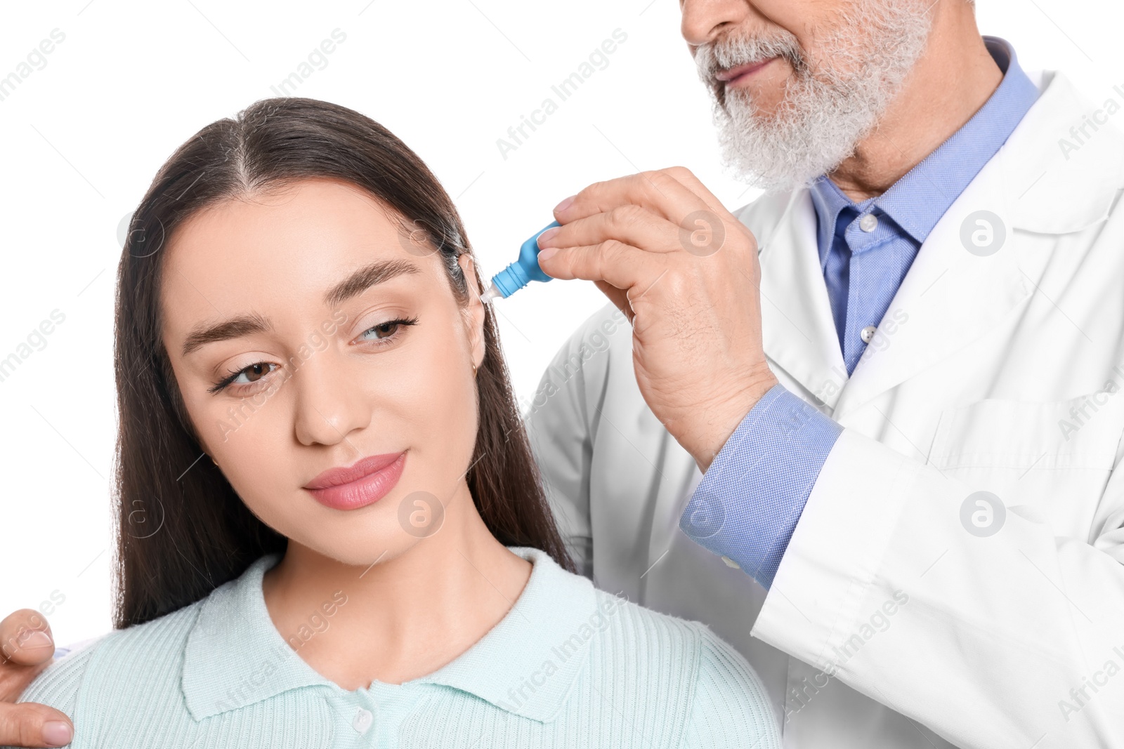 Photo of Doctor dripping medication into woman's ear on white background