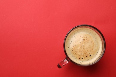 Photo of Fresh coffee in cup on red background, top view. Space for text