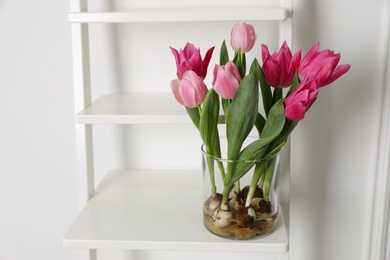 Photo of Beautiful tulips with bulbs on decorative ladder near white wall. Space for text