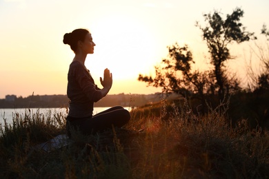 Photo of Young woman practicing yoga outdoors on sunset. Zen meditation