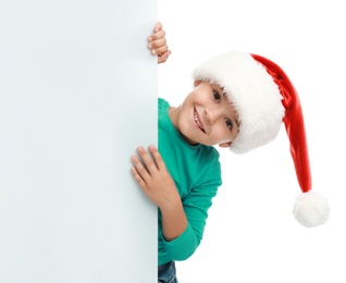 Photo of Cute little child wearing Santa hat on white background. Christmas holiday