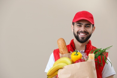 Man holding paper bag with fresh products on color background, space for text. Food delivery service