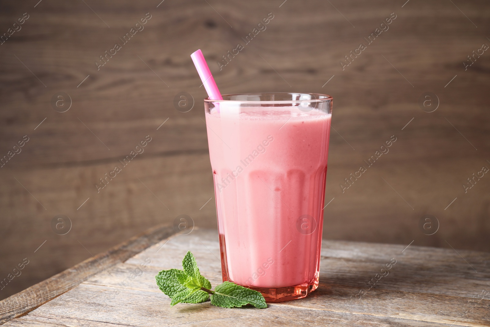 Photo of Tasty milk shake in glass on wooden table