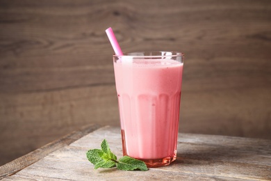 Photo of Tasty milk shake in glass on wooden table