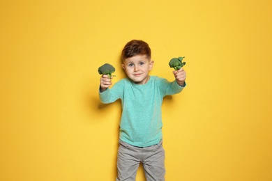 Photo of Adorable little boy with broccoli on color background