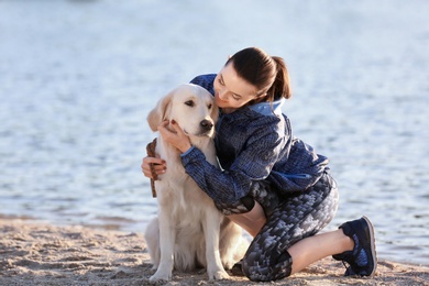 Young woman with her dog together on beach. Pet care