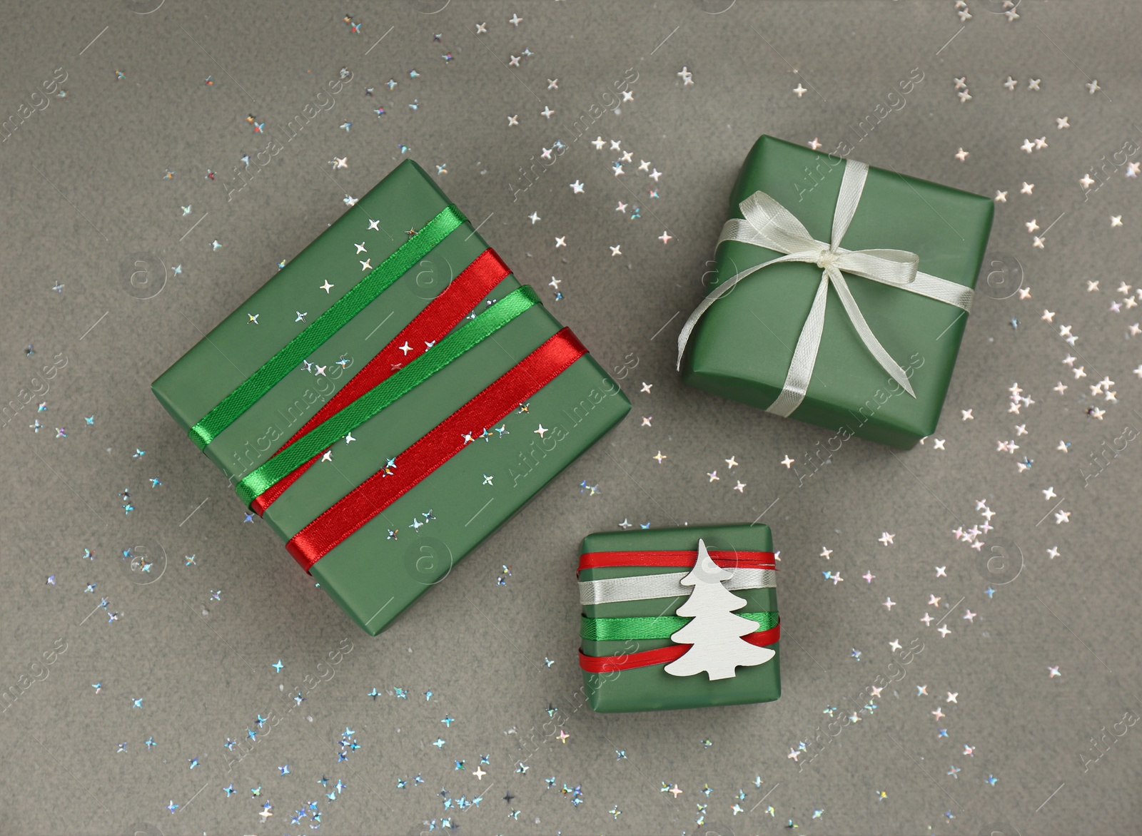 Photo of Christmas gift boxes and shiny confetti on grey background, flat lay