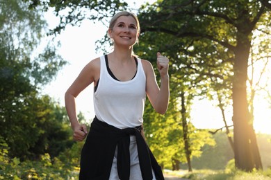 Photo of Woman running in park on sunny day. Healthy morning