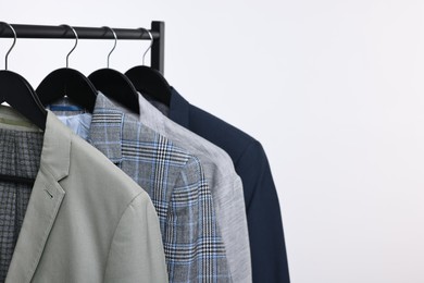 Photo of Dry-cleaning service. Many different clothes hanging on rack against white background, space for text