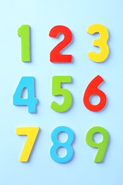 Colorful numbers on light blue background, flat lay