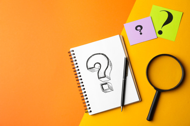 Photo of Flat lay composition of notebook, magnifier glass and cards with question marks on color background