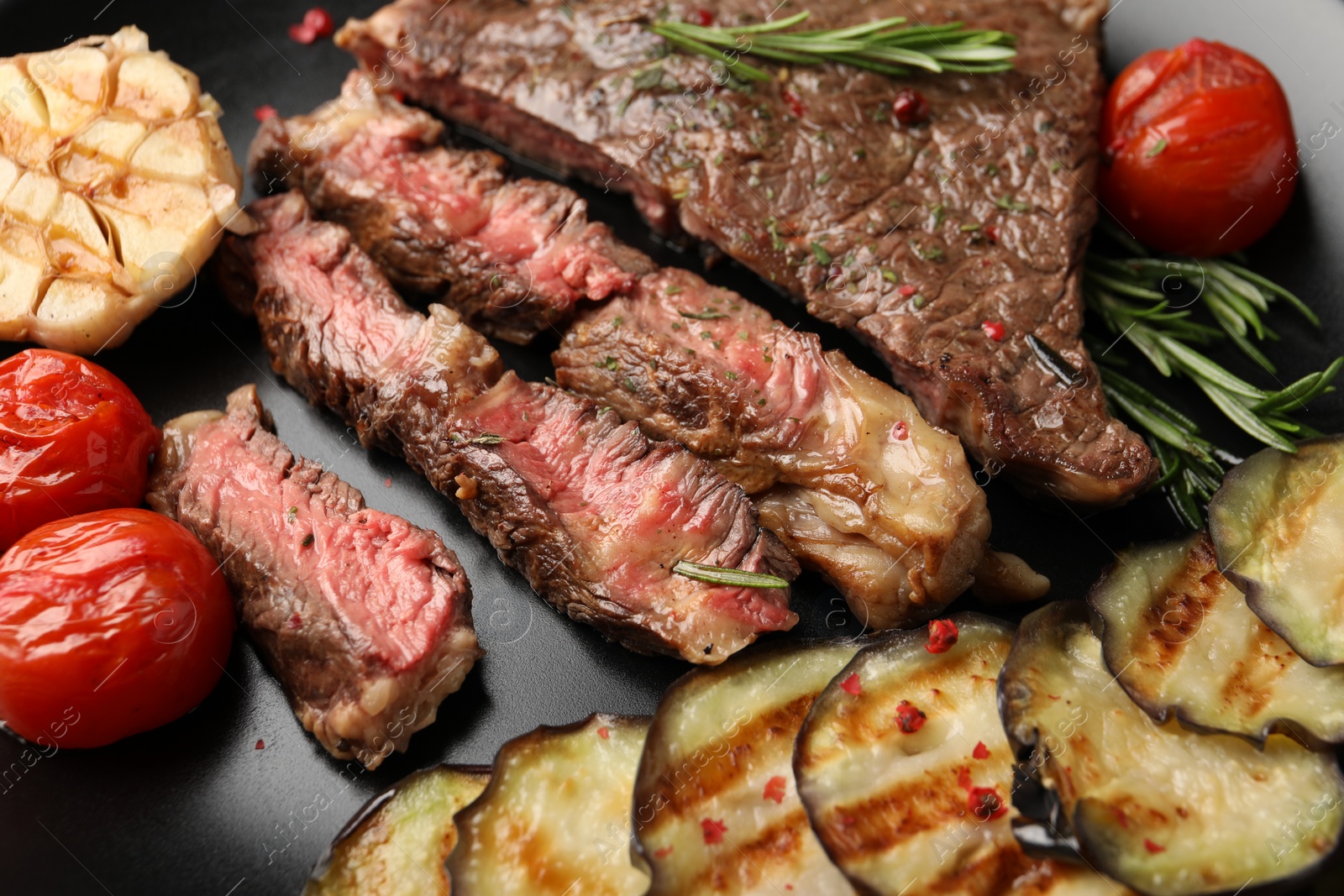 Photo of Delicious grilled beef steak with vegetables and spices on plate, closeup