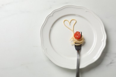 Photo of Heart made of tasty spaghetti, fork and tomato on white marble table, top view. Space for text