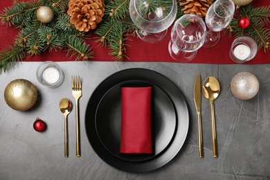 Photo of Christmas table setting with plates, cutlery, napkin and festive decor on grey background, flat lay