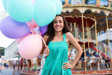 Photo of Attractive young woman with color balloons near carousel