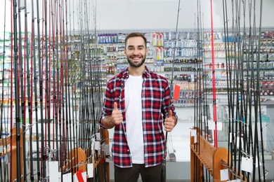 Man choosing fishing rod in sports shop