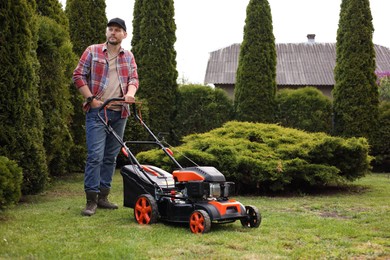 Photo of Man cutting green grass with lawn mower in garden