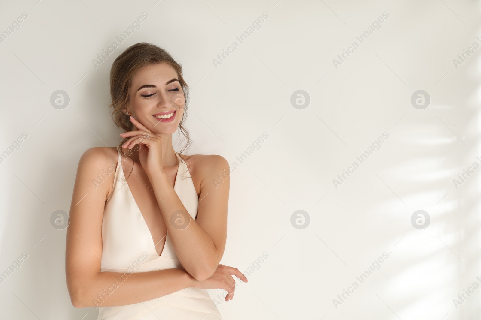 Photo of Young bride wearing beautiful wedding dress on light background. Space for text