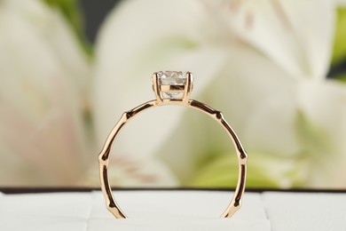 Photo of Beautiful engagement ring in box against blurred background, closeup