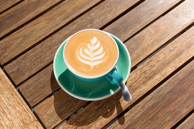 Cup of aromatic hot coffee and spoon on wooden table, above view