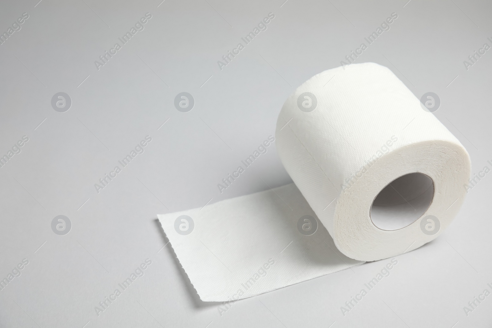 Photo of Toilet paper roll on grey background. Space for text