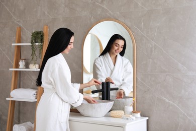 Beautiful young woman washing hands in bathroom