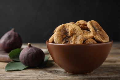 Photo of Bowl of tasty dried figs on wooden table. Space for text