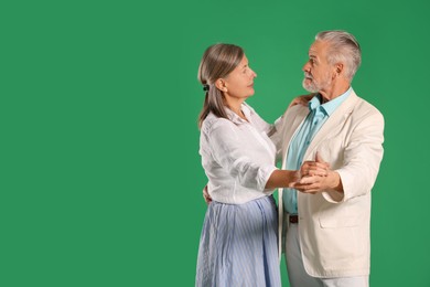 Photo of Senior couple dancing together on green background, space for text