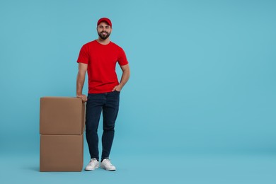 Photo of Happy courier with parcels on light blue background, space for text