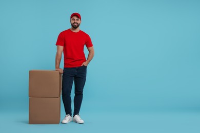 Happy courier with parcels on light blue background, space for text