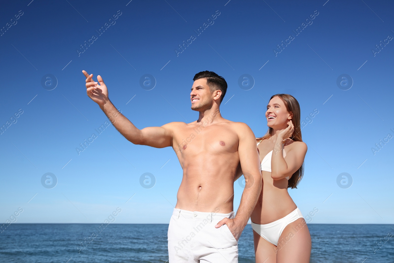 Photo of Woman in bikini and her boyfriend on beach. Happy couple