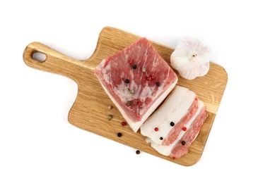 Photo of Board with cut pork fatback, pepper and garlic isolated on white, top view