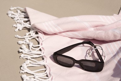 Photo of Stylish sunglasses, jewelry and pink blanket on grey surface, space for text