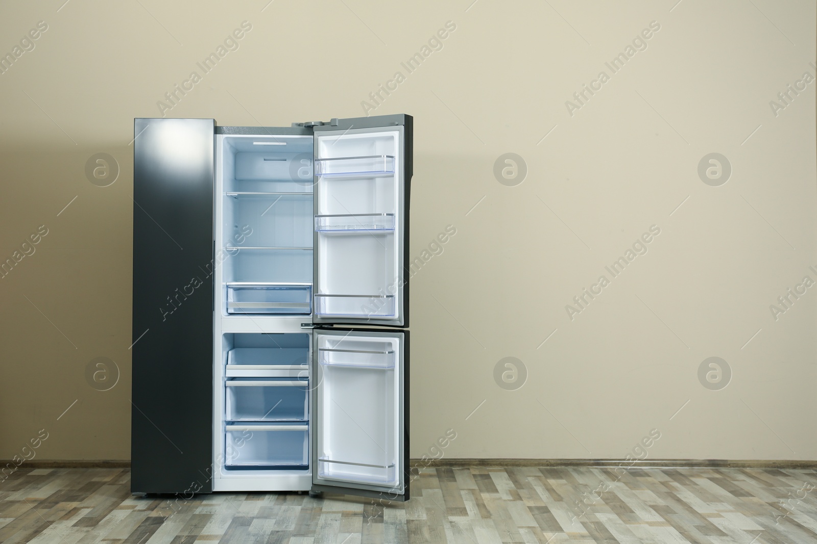 Photo of Modern refrigerator near beige wall, space for text