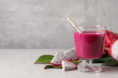 Photo of Delicious pitahaya smoothie and fresh fruits on light grey table, space for text