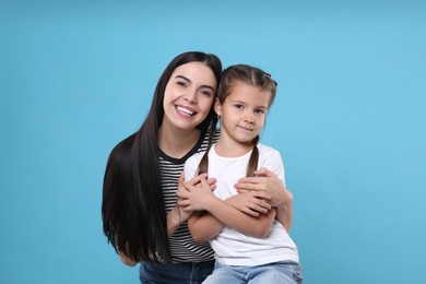 Photo of Happy woman with her cute daughter on light blue background. Mother's day celebration