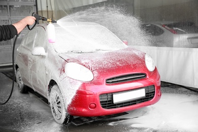 Photo of Worker cleaning automobile with high pressure water jet at car wash