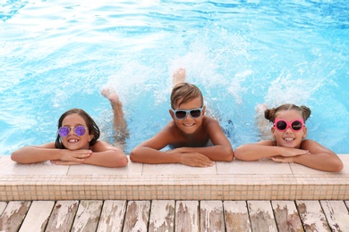 Happy children with sunglasses in swimming pool on sunny day