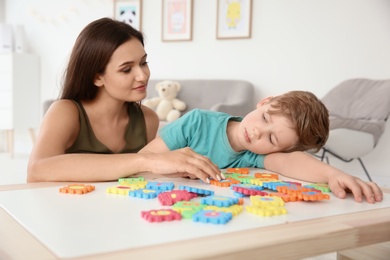 Photo of Young woman and little boy with autistic disorder playing at home
