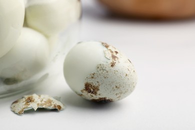 Photo of One boiled quail egg in shell on white table, closeup