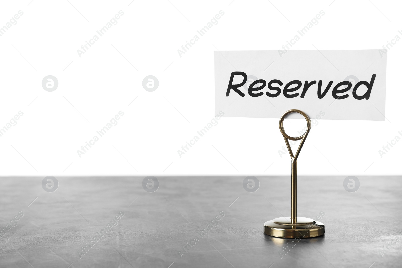 Photo of Elegant sign Reserved on grey table against white background, space for text