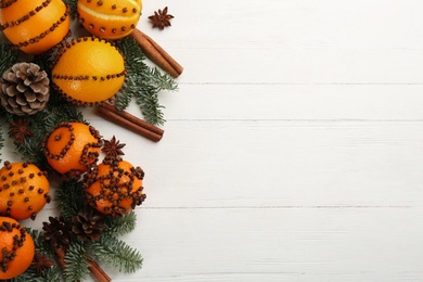 Photo of Flat lay composition with pomander balls made of fresh tangerines on white wooden table. Space for text