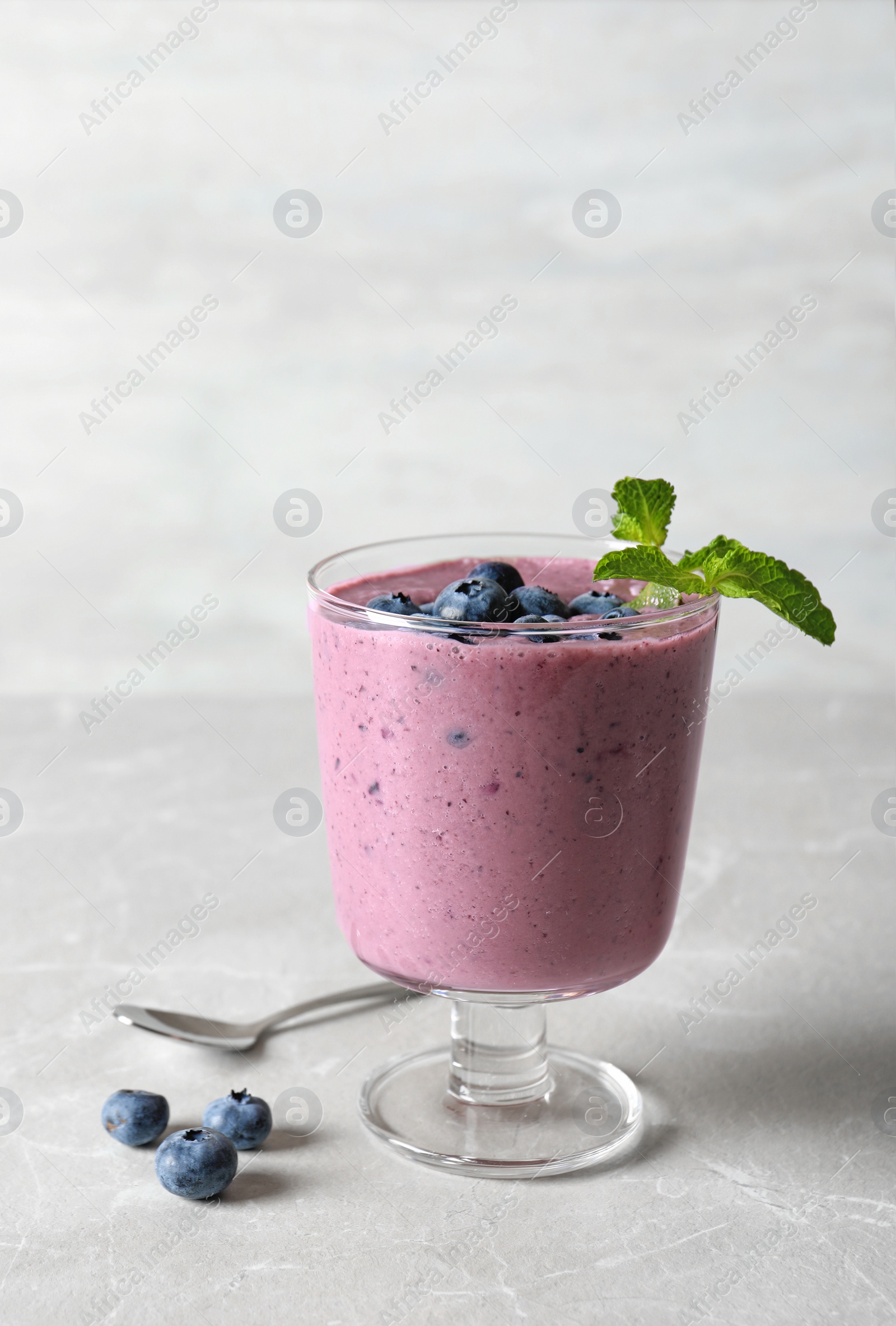 Photo of Glass with blueberry smoothie on grey table