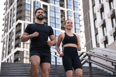 Photo of Healthy lifestyle. Happy couple running on steps outdoors, low angle view