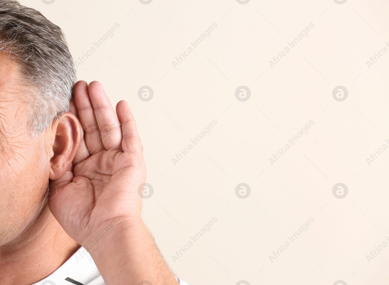 Photo of Mature man with hearing problem on light background, closeup. Space for text