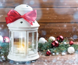 Christmas lantern with burning candle and festive decor on wooden table