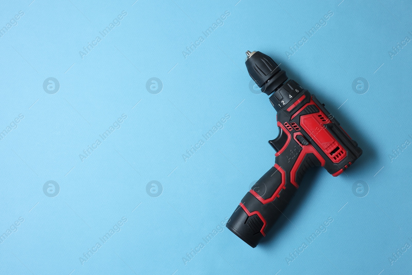 Photo of Electric screwdriver on light blue background, top view. Space for text
