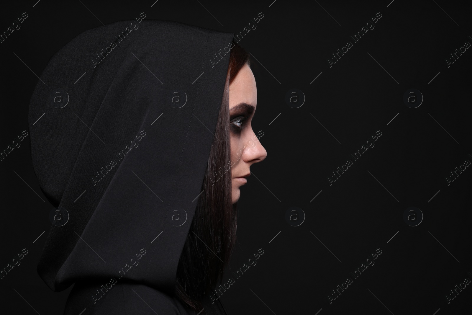 Photo of Mysterious witch with spooky eyes on black background, space for text