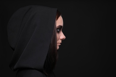 Photo of Mysterious witch with spooky eyes on black background, space for text