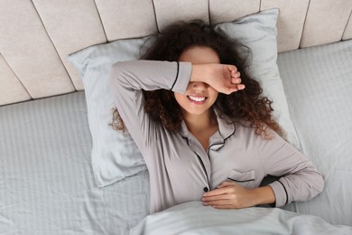 Photo of Beautiful African American woman lying in bed, top view